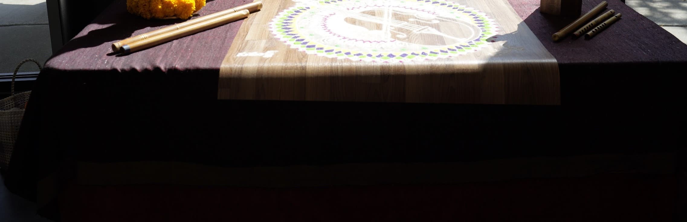 A still life of a rangoli, brass finial and tulips on a sunlit windowside table